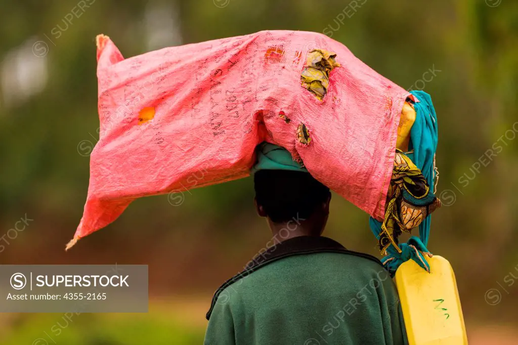 A Rawandan woman walks to market with a bag of clothes to be sold on her head. It is not uncommon for a woman to carry up to 80 to 100 pounds on their heads.