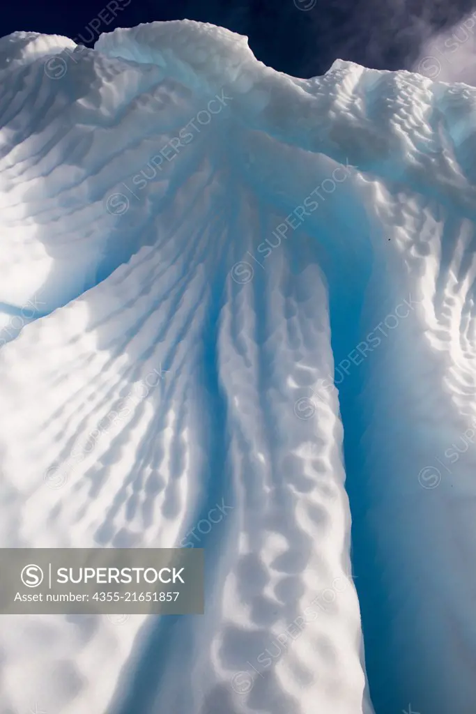A large striated blue iceberg off of Cuverville Island, Antarctica