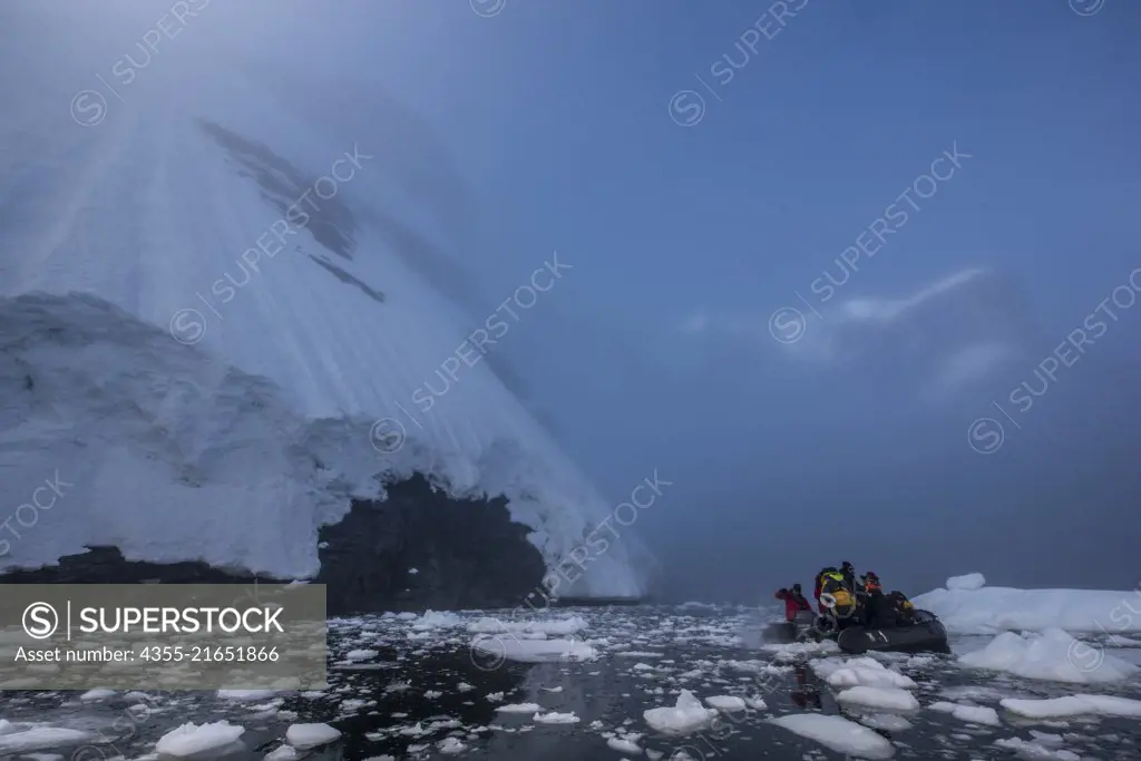 Sun rises through heavy fog showing large icebergs in Blackhead, Antarctica