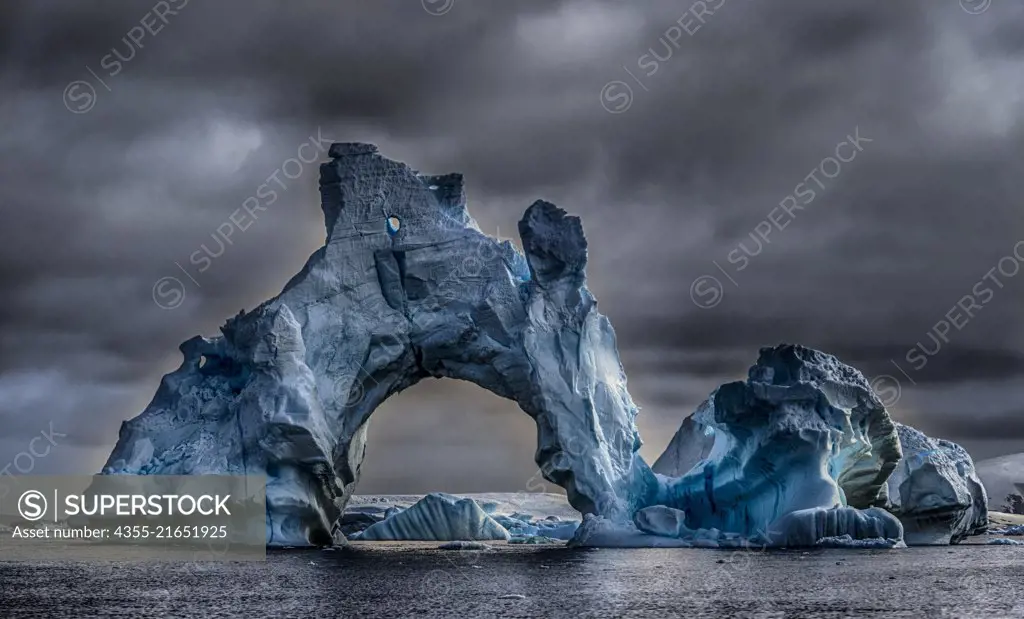 A majestic iceberg with a large arch in  Cape Tuxen, Antarctica