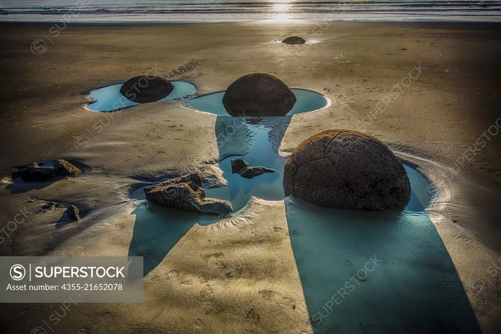 The Moeraki Boulders are large spherical boulders lying along a stretch of Koekohe Beach on the Otago coast of the South Island in New Zealand