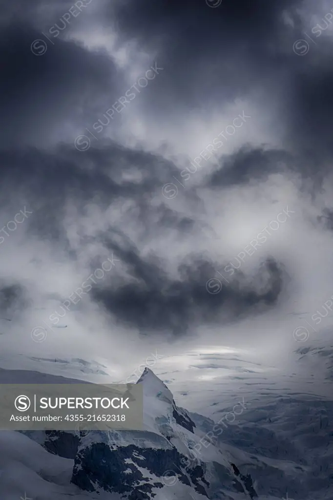 Clouds that resemble the Jokers face from Batman hang over glacial ice in Wilhelmina Bay on the Antarctic Peninsula.