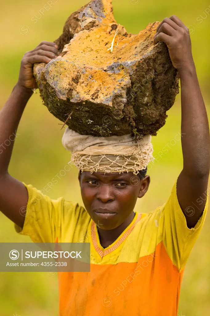 Rwanda, Gahilikiro, Young man carrying rock on his head