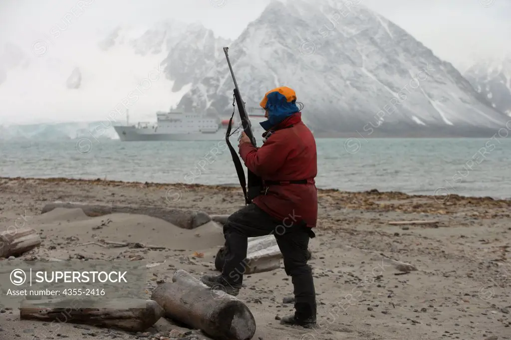 Norway, Svalbard Islands, Guide standing with loaded rifle to ward off any Polar Bears