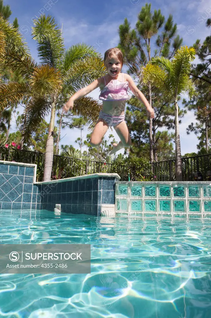 USA, Florida, Young girl jumping into swimming pool