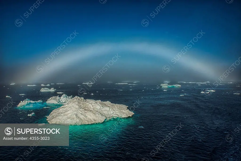 Icebergs floating on water with fogbow in the background, Bernstorff Isfjord, Sermersooq, Greenland
