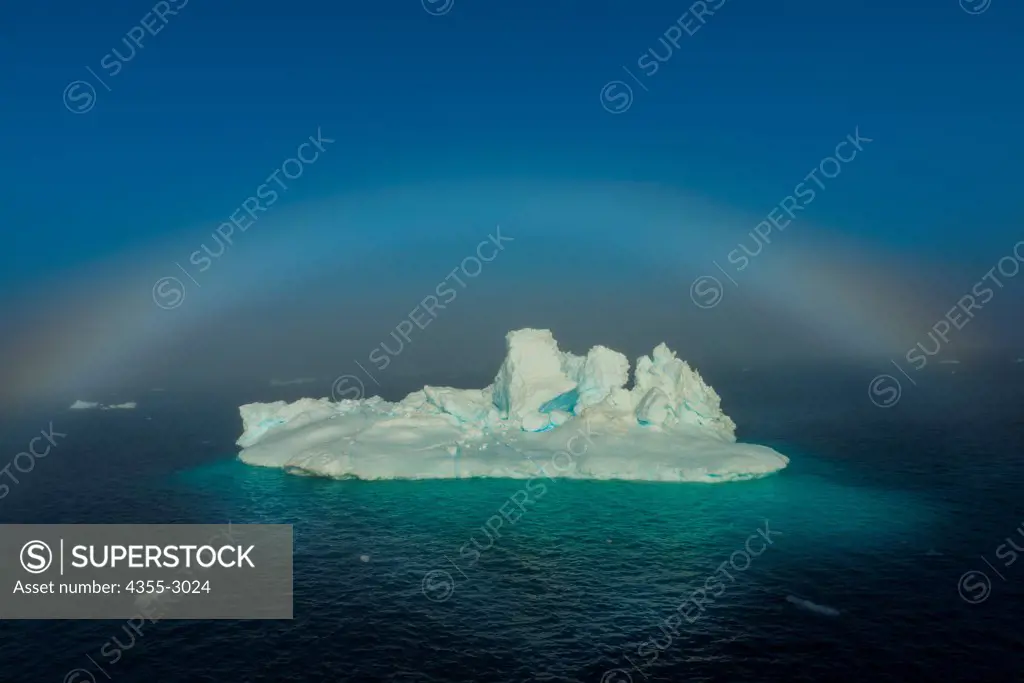Tabular iceberg floating on water with fogbow in the background, Bernstorff Isfjord, Sermersooq, Greenland