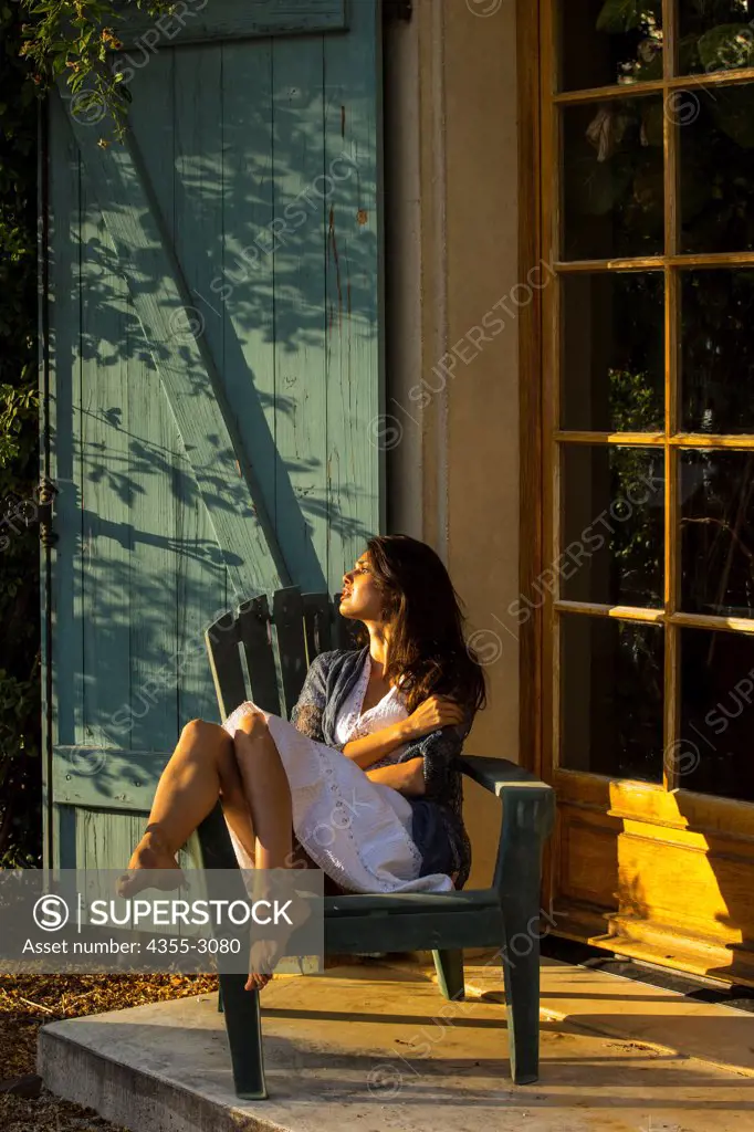Woman resting on an Adirondack chair on a porch, Mendocino, California, USA