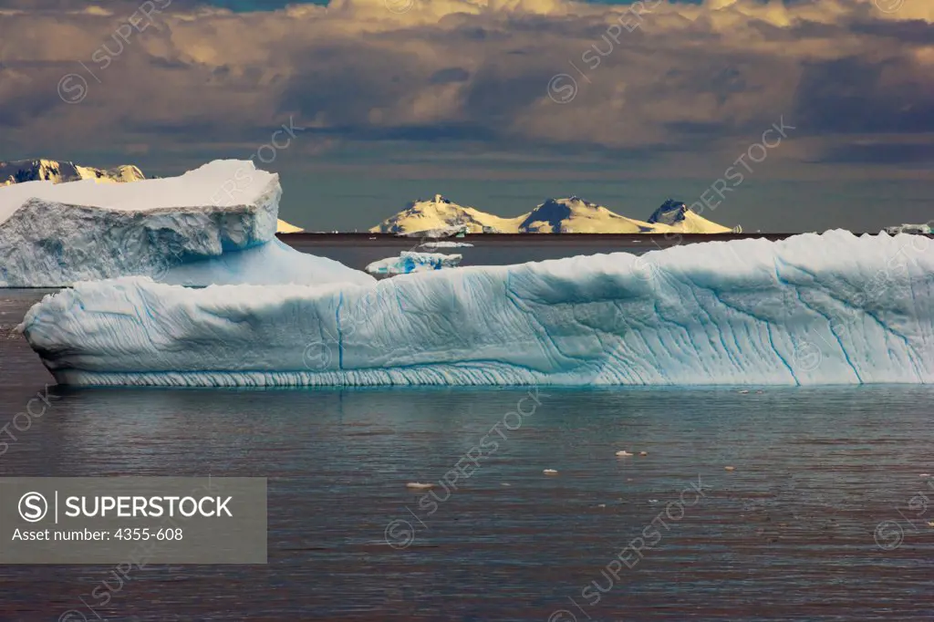 Blue Eroded Icebergs With the Antarctic Coast in the Background