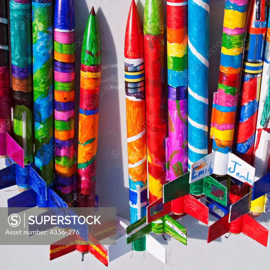 A row of brightly painted model rockets at a rocketry launch event.