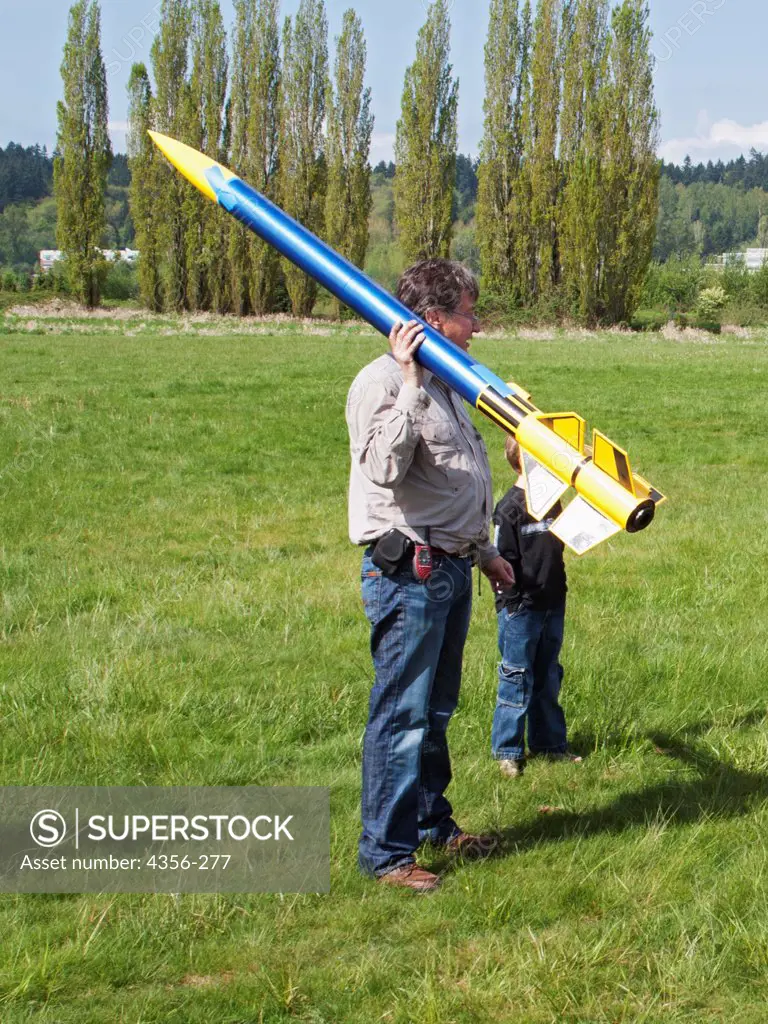 A man with a large model rocket at a rocketry launch event in east King County.