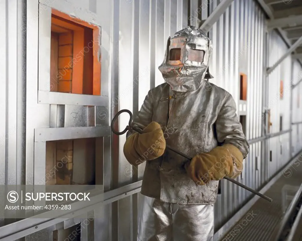 Worker with Safety Clothing Beside a Furnace for Melting Glass