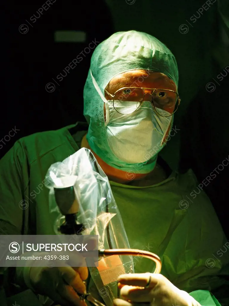 A masked surgeon uses an endoscope during a minimally invasive operation.