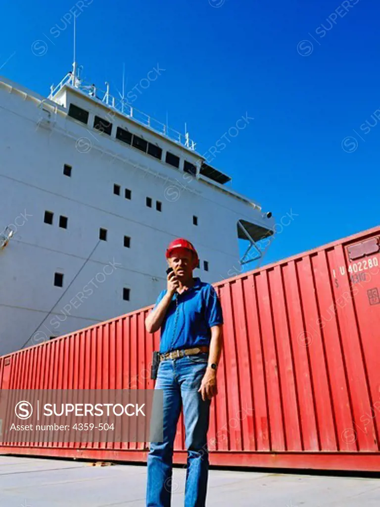 A dock worker in front of a cargo container on a cargo ship.