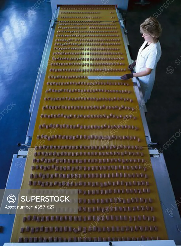 Women working by a conveyor belt and checking the quality of chocolate bars