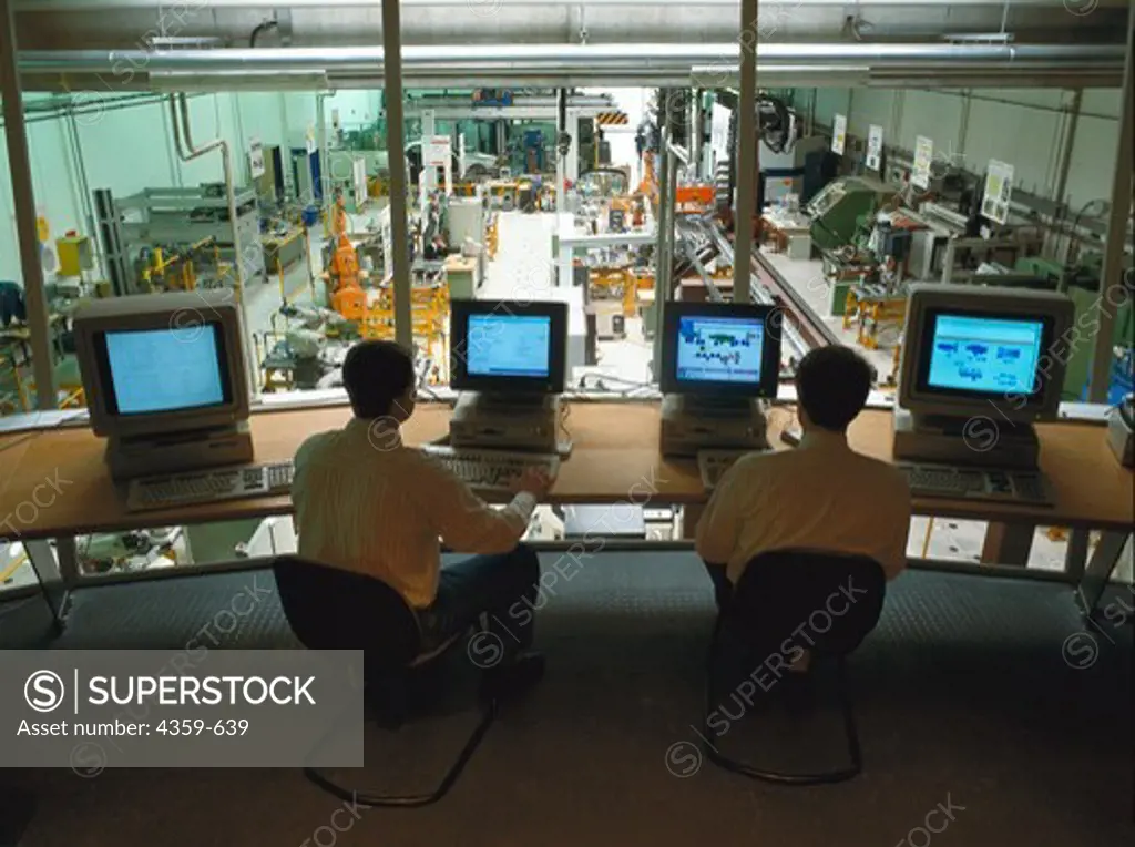 Control room of a computer controlled factory with a view into the production hall