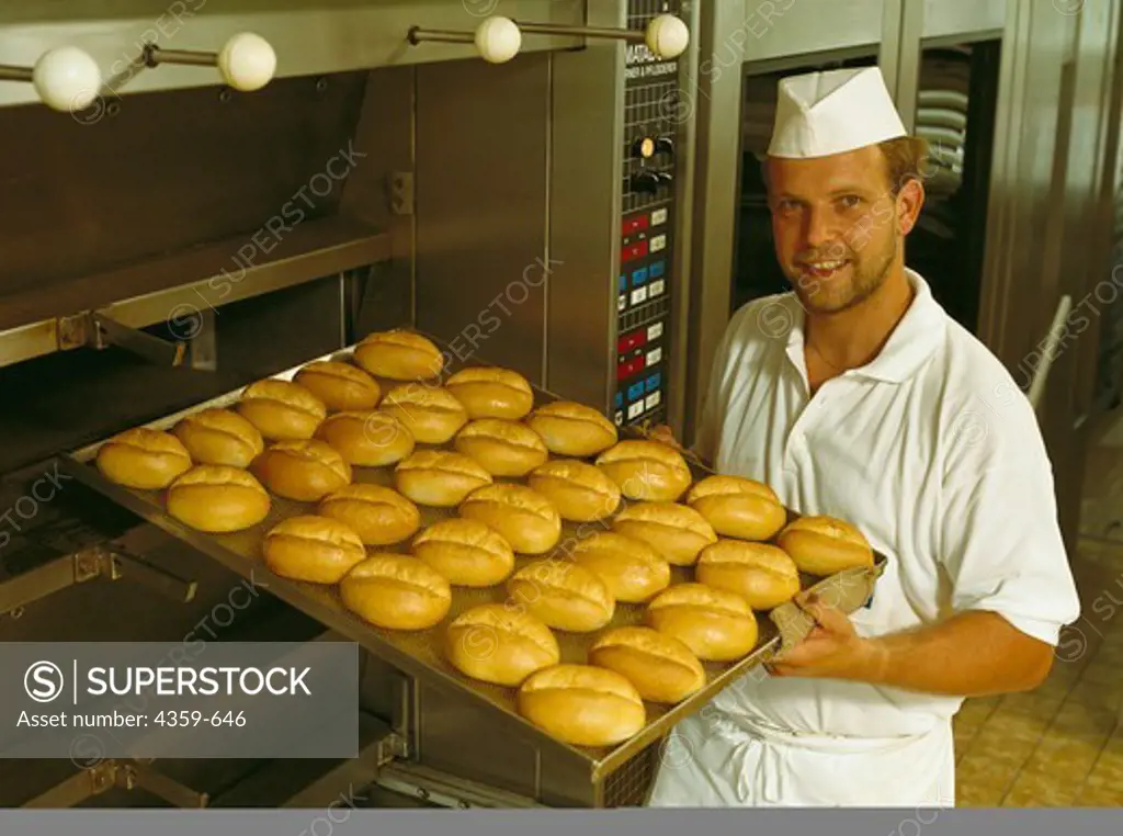 Baker removing rolls from oven
