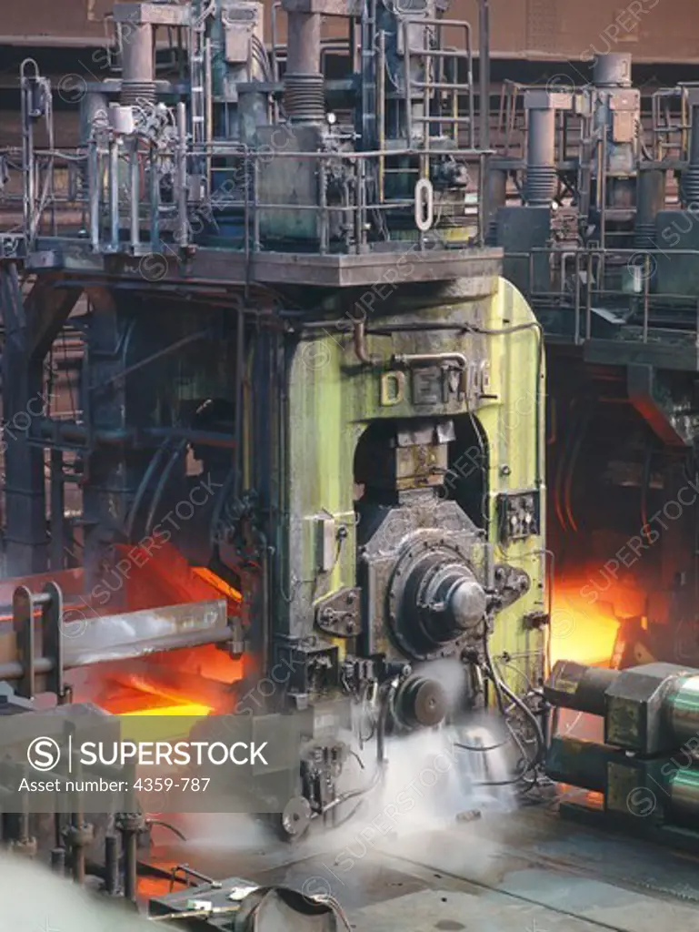Strip of glowing steel being rolled in rolling mill