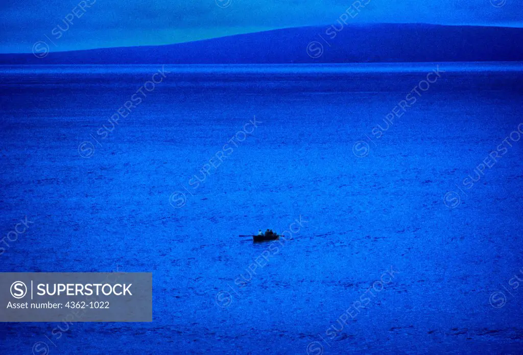 Ireland, Three men at dawn in rowboat on Irish Sea near Ballybunion