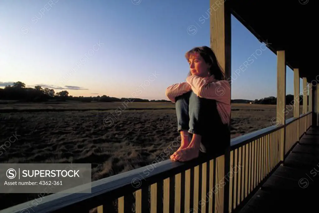 Young Woman Watches the Sunset from Porch