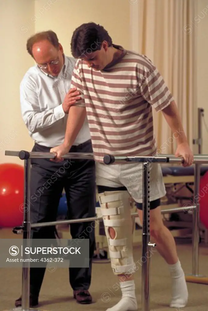 Physical Therapist Helps Patient with Injured Leg to Walk