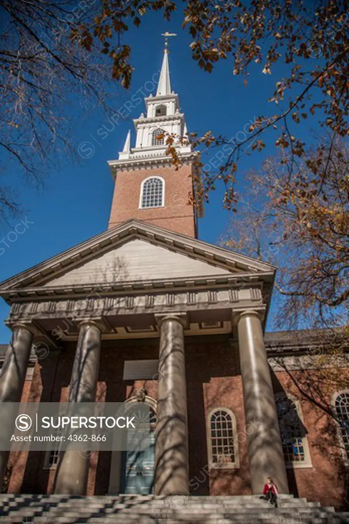USA, Massachusetts, Cambridge, Harvard University, Young woman in red jacket sitting on steps of Harvard University's Memorial Chapel