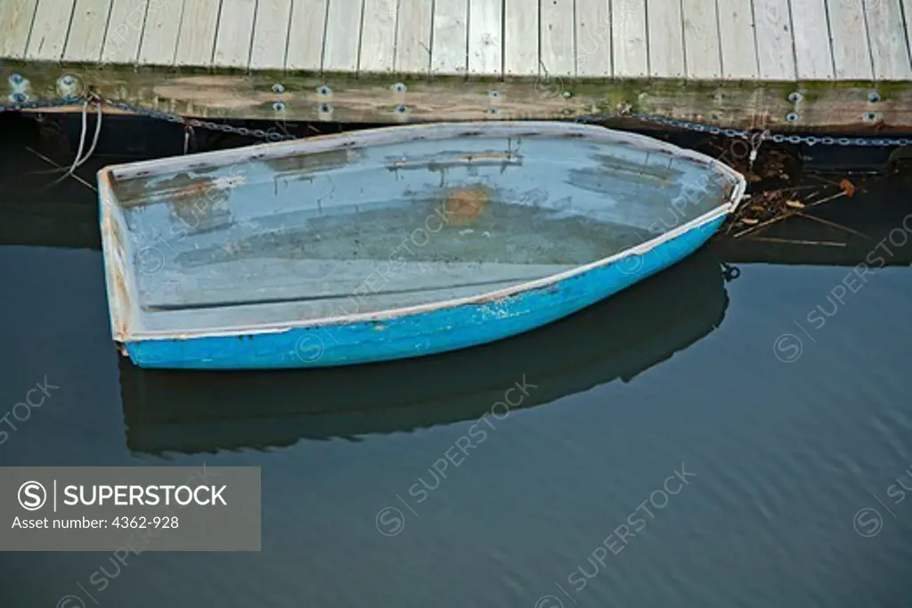 USA, Massachusetts, Gloucester, Blue rowboat without oars and half filled with rainwater at dock