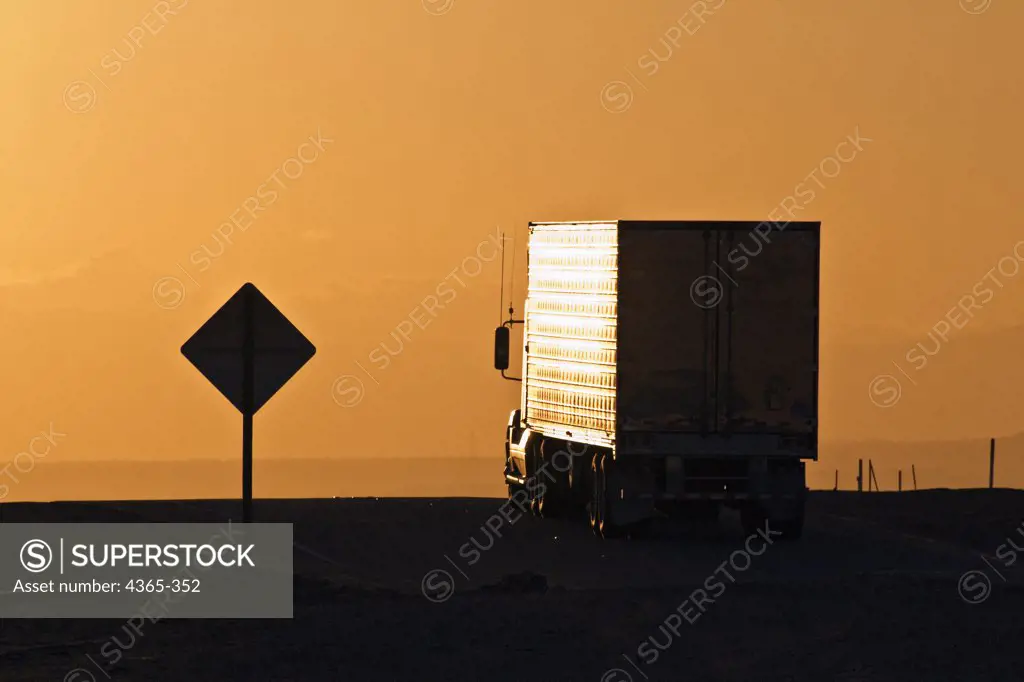 A truck at a crossroads at sunset.