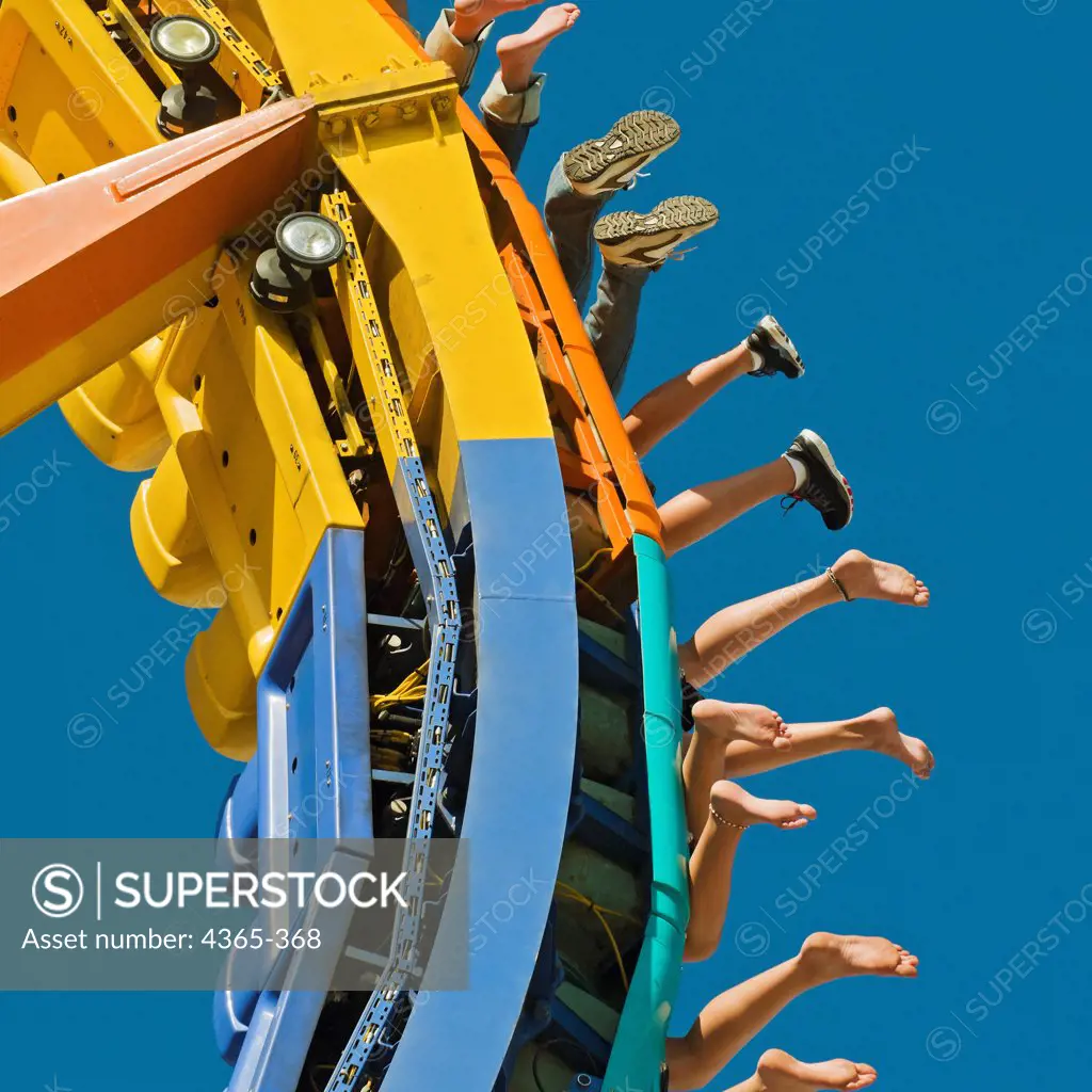 People's feet dangle off of an amusement ride.