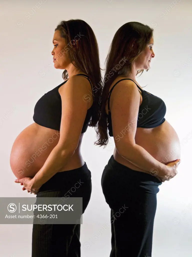 Two pregnant women back to back. The woman on the left is pregnant with twins. The woman on the right gave birth 13 hours after the picture was taken.