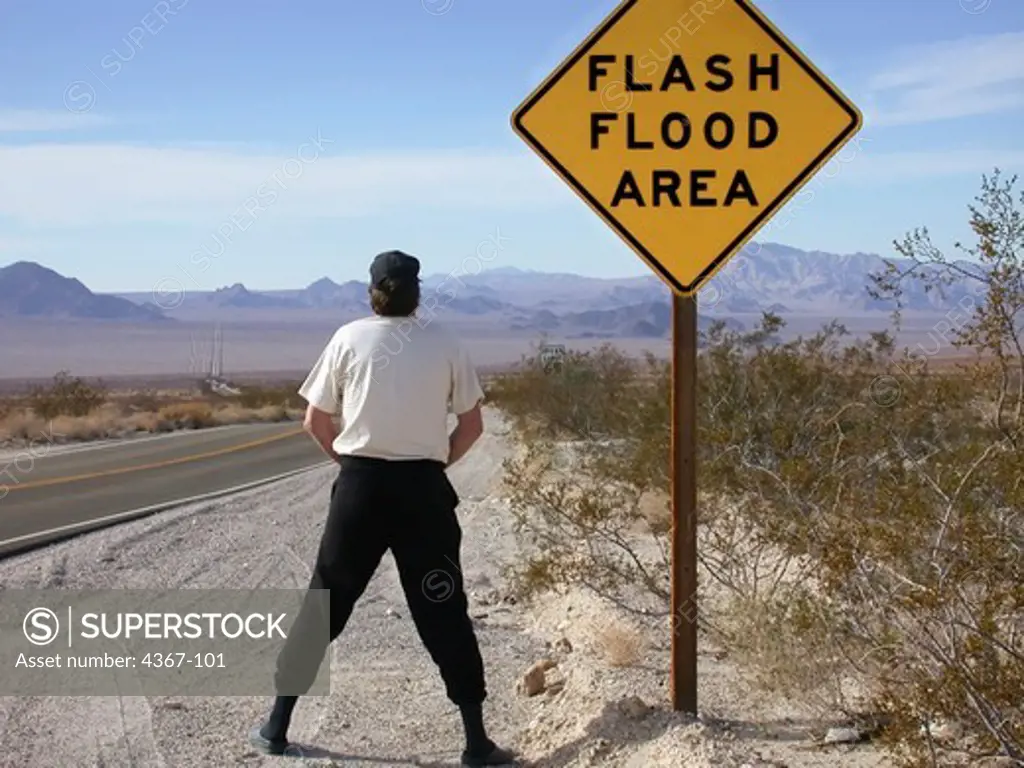 Man Urinating by Flood Sign