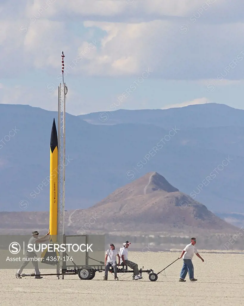 A small group of people pull a yellow rocket 'The Minnesota Youbetcha', out to the launch range at BALLS, an experimental rocketry event in the Black Rock Desert of northern Nevada.