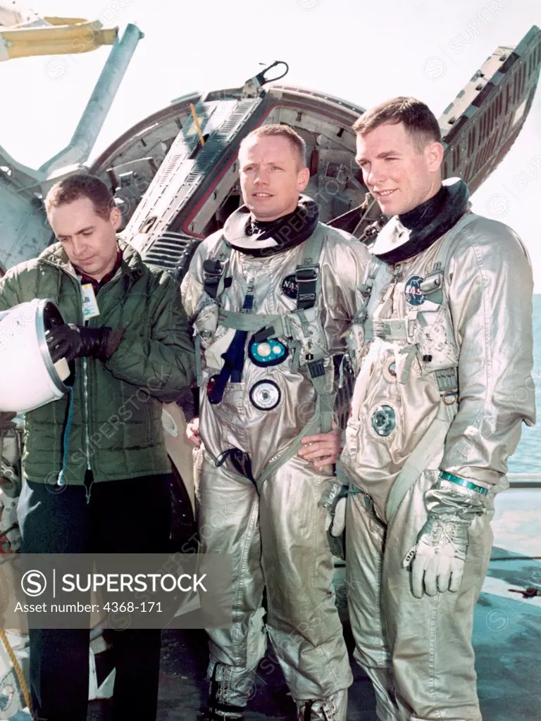 Astronauts Neil A. Armstrong (center), command pilot, and David R. Scott (right), pilot of the Gemini 8 prime crew, are suited up for water egress training aboard the NASA Motor Vessel Retriever in the Gulf of Mexico. At left is Dr. Kenneth N. Beers, M.D., Flight Medicine Branch, Center Medical Office.