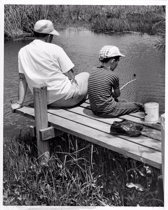 Father and son sitting on jetty and fishing