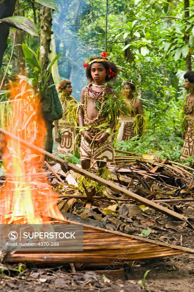 A girl watches sago loaves cooking in a palm leaf during a village experience and cultural event, Tufi, Papua New Guinea.  Participating clans were the Fighoya, Kandoro, Tewari, Gaboru, and Safu from the villages of Koje, Kofure, Iagirua, Koave, Marabade, Fodoma, Bekoyana, Koyatona.