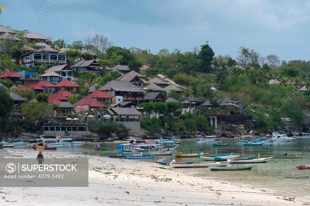 Boats with a woman carrying basket on head on the beach, Nusa Lembongan, Bali, Indonesia