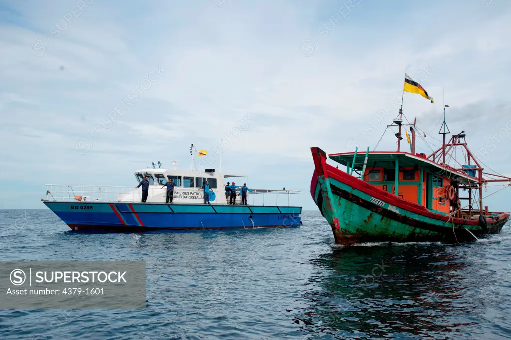 Fisheries department officials pull up next to a trawler hauling net to conduct a spot check, Brunei
