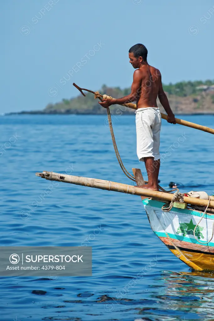 A man with a traditional whaling harpoon, Lamalera, Lembata Island, Eastern Indonesia. The traditional method of whaling here is to leap high in the air off the prow platform, using a downward thrust stab.