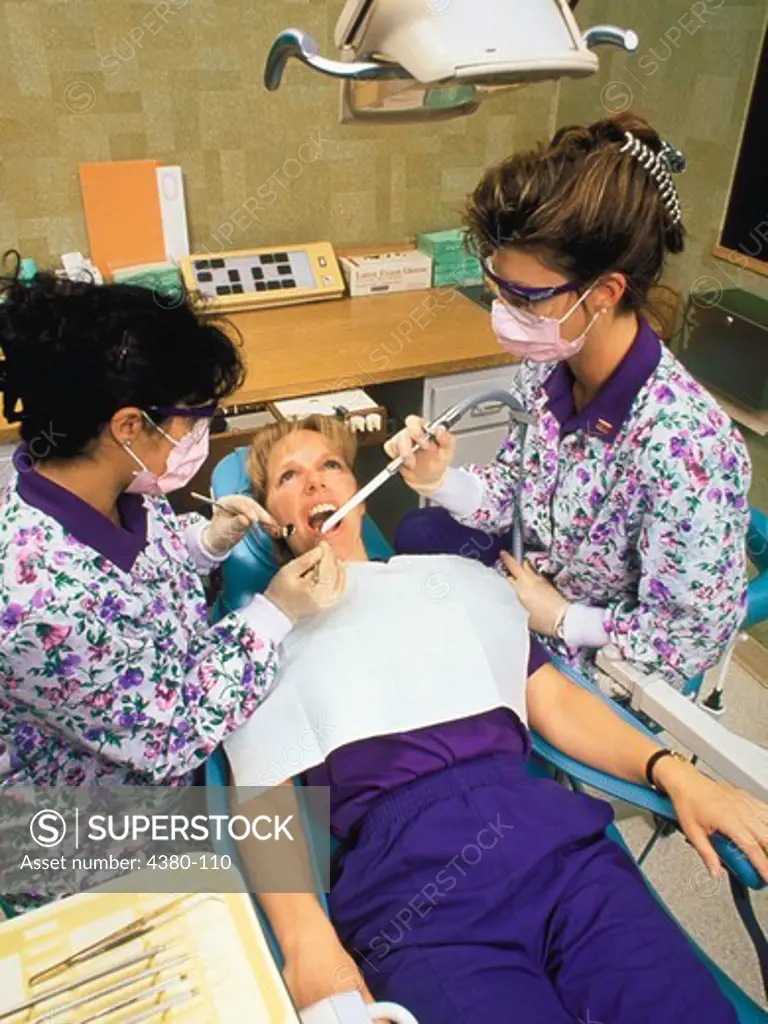 A Dental Hygienist and Technician Perform A Dental Exam on a Patient in the Dentist Office