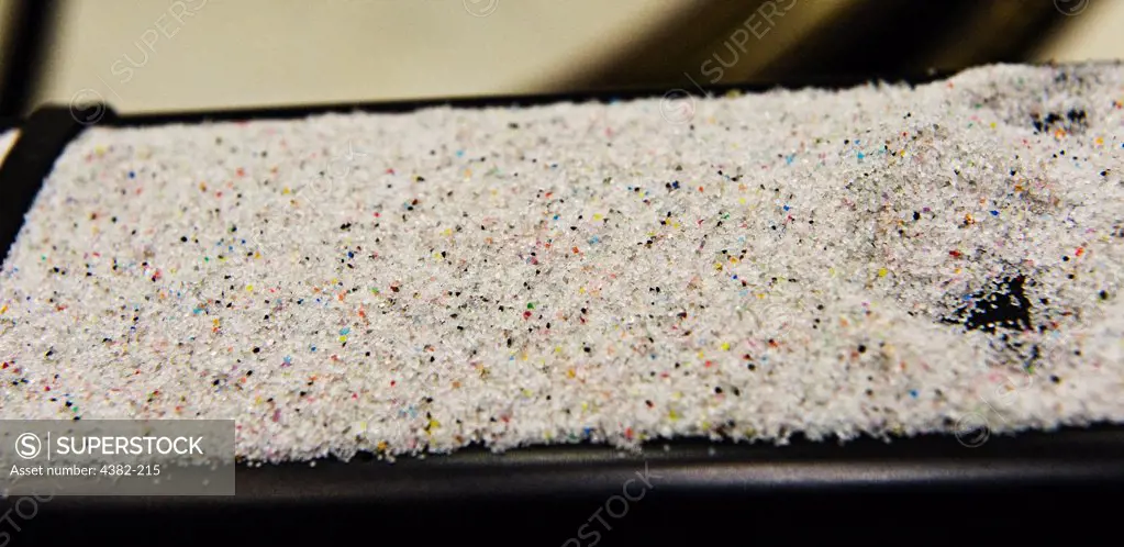 Sand - actually tiny plastic beads - and colorful pieces of what was aircraft paint are the remainders of the aircraft depainting process at  the 402 Maintenance Support Squad, Corrosion Control Flight, Robins Air Force Base. (U.S. Air Force photo by Lance Cheung)