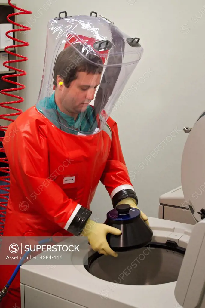 While wearing his air tight safety suit in this 2007 image, CDC microbiologist Dr. Scott Smith is in the process of placing a rotor cuff containing tubes of virus particles and cellular debris into a high-speed centrifuge. This activity is taking place inside the confines of the organizations Biosafety Level 4 (BSL-4) laboratories. The Special Pathogens Branch mission focuses mainly on viral hemorrhagic fevers (VHFs), such as Ebola hemorrhagic fever, Lassa fever, hantavirus pulmonary syndrome (