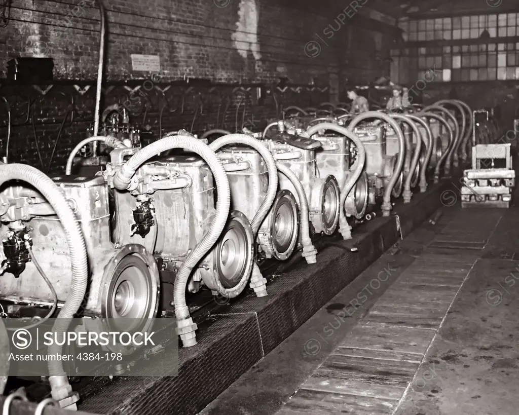 This historical 1947 photograph was provided by the Center for Disease Control's (CDC), National Institute for Occupational Safety and Health (NIOSH). It depicted an indoor array of combustion engines that were in the process of being performance tested at the Pacific Car & Foundry Co., Renton, Washington. The exhaust produced by these engines had to be removed through a ventilation system, to which each engine was engaged by way of corregated hoses connecting each engines block manifold to the