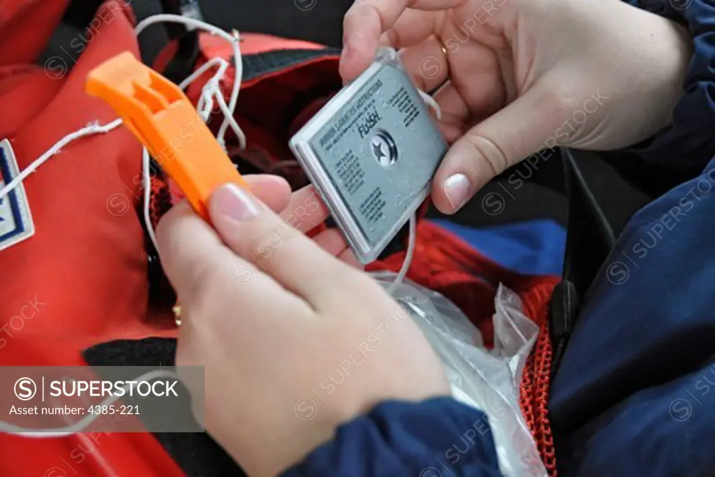Coast Guard Seaman Samantha Randall, 20, of Coast Guard Station King's Point in King's Point, N.Y., displays a personal Emergency Position Indicating Radio Beacon (EPIRB) required to be carried by U.S. Coast Guardsmen who are underway. The Coast Guard strongly urges mariners to be prepared in case of emergencies and to bring survival equipment such as signalling and sound devices, a personal EPIRB, cell phone, radio and lifejackets while underway to increase chances of survival in the event some