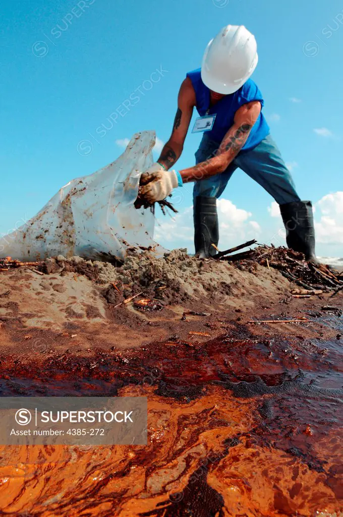 GRAND ISLE, La. - A worker cleans up oily waste on Elmer's Island, just west of Grand Isle, La., May 21, 2010.  Hundreds of workers are cleaning up oil from the damaged Deepwater Horizon wellhead that finally reached the shore a month after the rig exploded, killing 11 people.