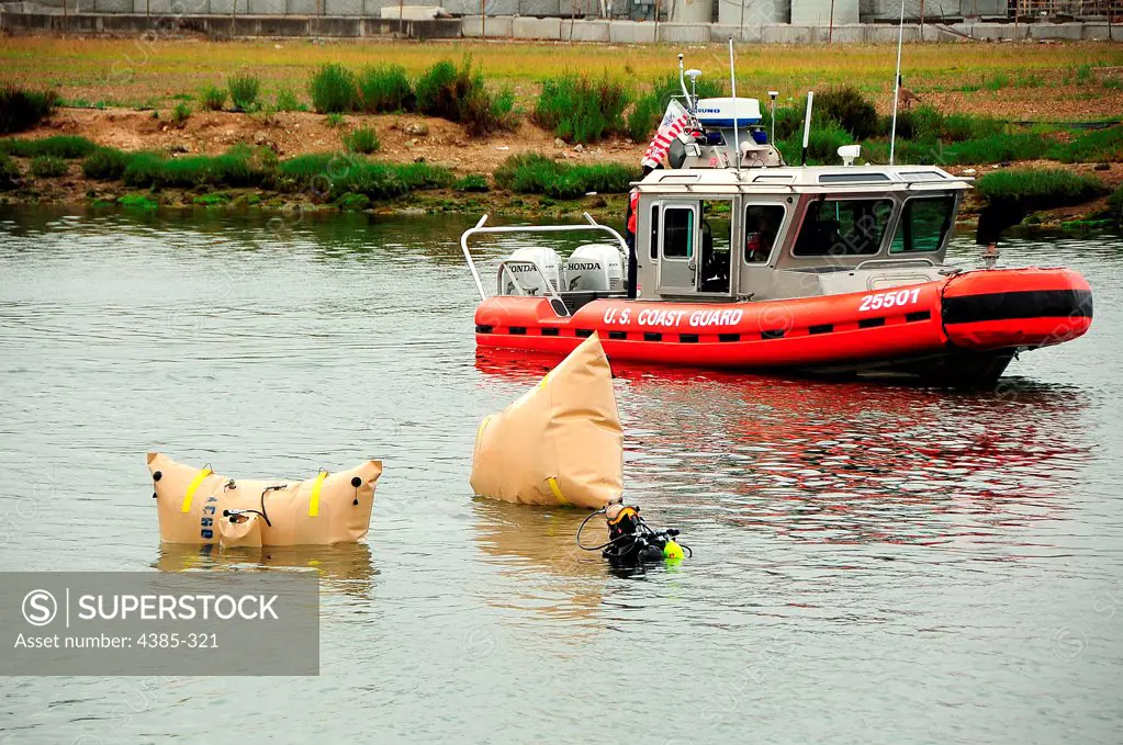 OAKLAND, Calif. -- A diver, from the Alameda County Sherriff's Office, attaches airbags to a sunken vehicle as a Coast Guard 25-foot Response Boat-Small boat crew provides a safety area during a response in the Oakland Estuary, Thursday, June 9, 2011.