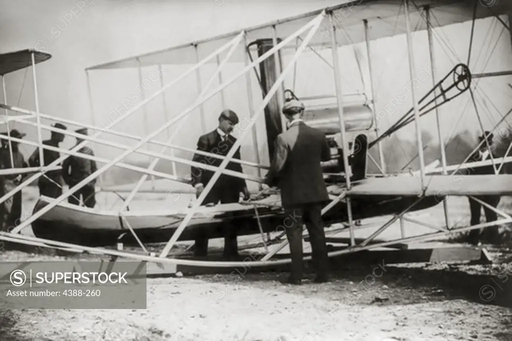 Wilbur Wright Checks Canoe Attachment on Airplane