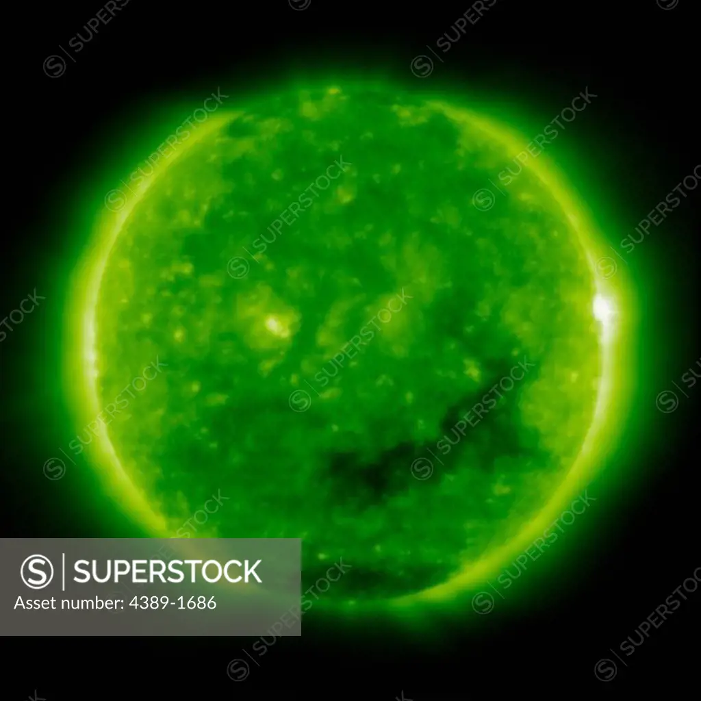 The dark coronal hole in the Sun's lower region is a 'open' magnetic area through which the solar wind follows, seen in this view from the Solar and Heliospheric Observatory (SOHO)'s Extreme ultraviolet Imaging Telescope (EIT) 195 Angstrom instrument.