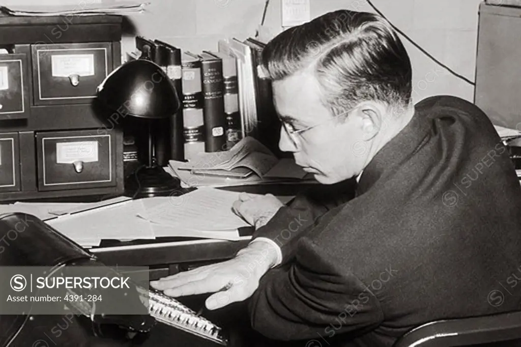 A scientist seated at a desk working on scientific calculations.