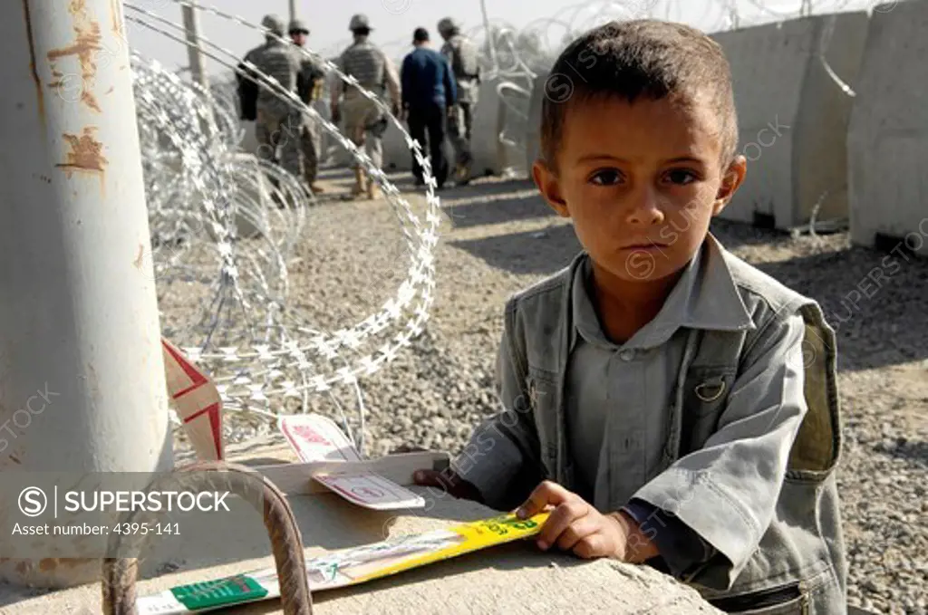 A young Afghan boy waits at the beginning of the entry control point of Kabul International Airport, Oct 22, after receiving a toy plane from a group of Air Force personnel.  The toy planes were given out with soccer equipment to a group of local children from the Kabul Youth Soccer League .