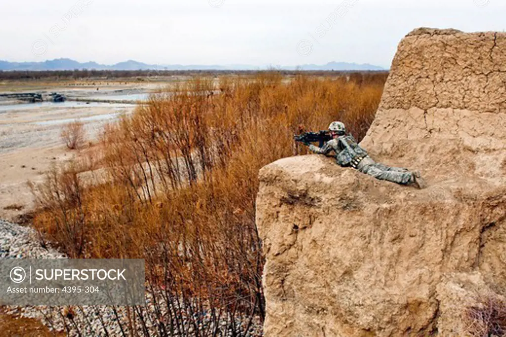 Spc. Jeremy Burton, armored crewman, assigned to 2nd Squad, 3rd Platoon, Company C., 1st Battalion, 66th Armored Regiment, 1st Brigade Combat Team, 4th Infantry Division, lays in the prone position on cliff overlooking the Arghandab River Valley Jan. 31